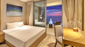 Een hotelkamer met een groot bed, een bureau, een stoel, een nachtkastje, een lamp, een schilderij en uitzicht op zee en een raket door het raam.