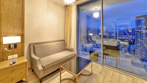 Een moderne hotelkamer met een bank, een klein tafeltje en een groot raam met uitzicht over de stad.