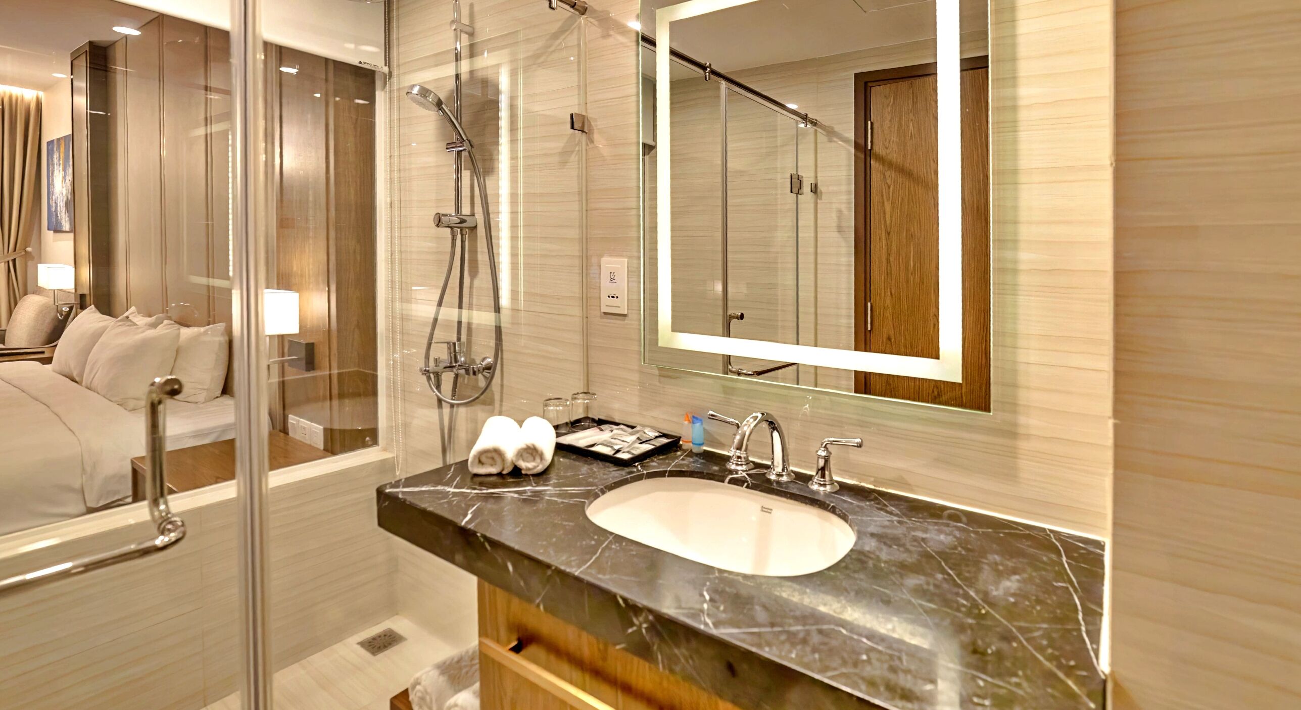 A modern bathroom with a glass-enclosed shower, a marble sink, and a large mirror.