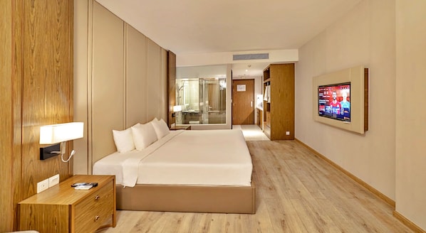 A hotel room with a large bed, bedside table, and a TV mounted on the wall. - S79 Suite MOcean Panorama Nha Trang (Nha Trang)