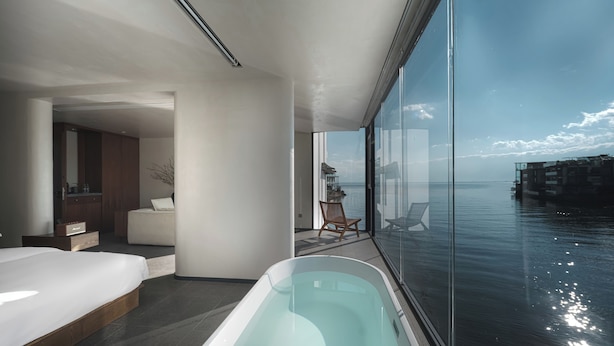 A modern bedroom with a large window, a bathtub, and a view of the sea. - Mangshu Taotangzhiqiu Seaview Hotel (Dali)