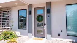 A modern building entrance with a door marked '16', a small garden, and a window with blinds. - GUEST FAVORITE - Pool & Pickleball -Clean & Comfortable-St George Home near Zion (St George)