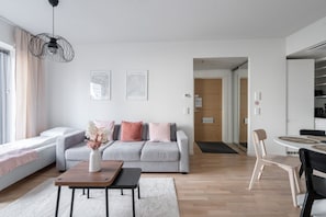 A modern living room with a grey sofa, a coffee table, and a dining area with a table and chairs.