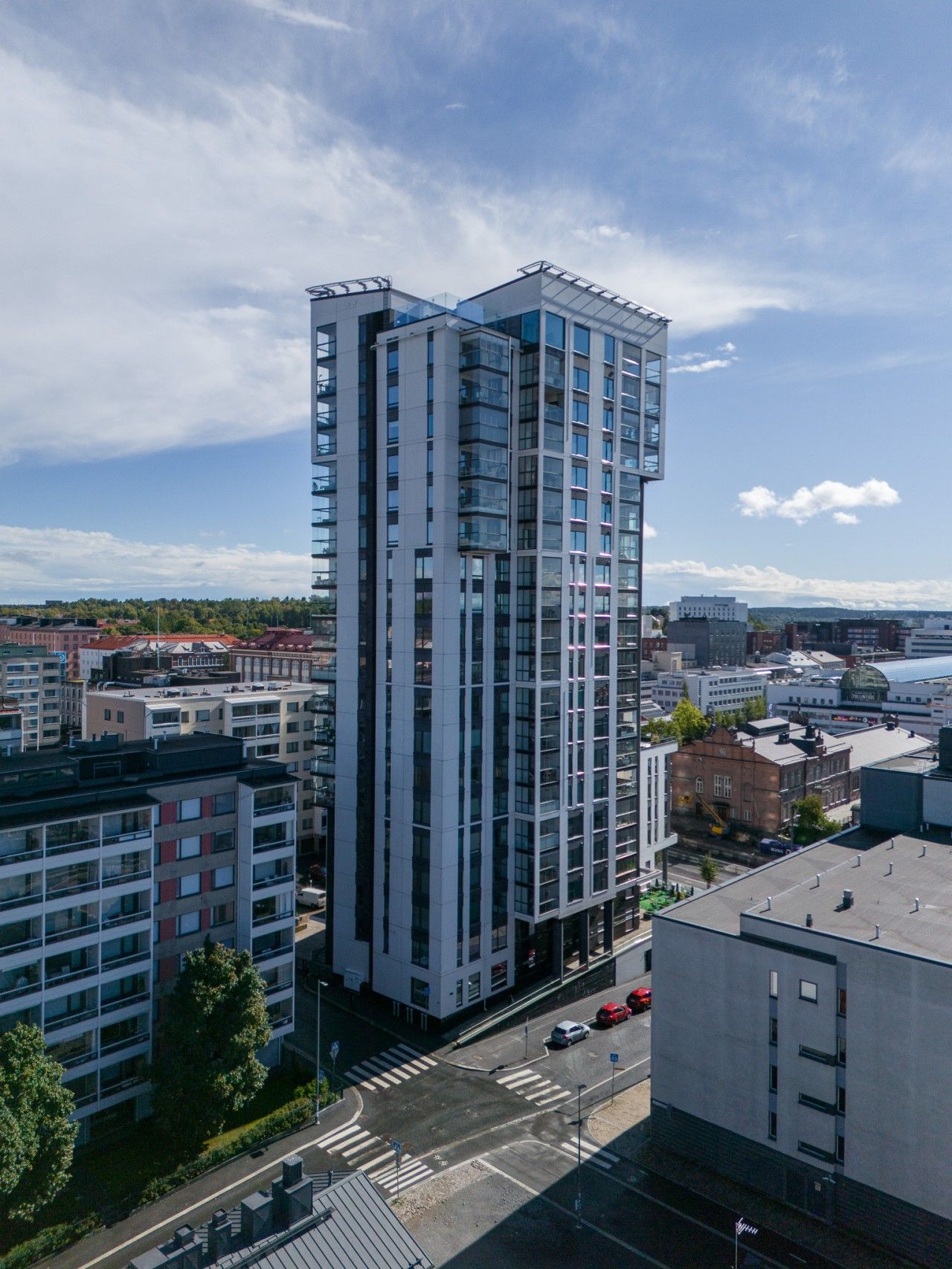 A modern high-rise building with multiple floors, large windows, and a corner entrance.