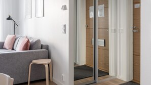 A modern living room with a grey sofa, a small wooden table, and a glass door leading to a wooden room. - Stylish New 1BR Home with Sauna, Hosts 4 Guests (Tampere)