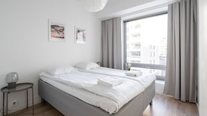 A modern hotel room with a large bed, a bedside table, and a window with curtains. - Stylish New 1BR Home with Sauna, Hosts 4 Guests (Tampere)