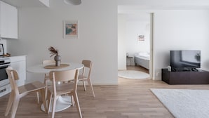 A modern, minimalist living space with a dining area, a kitchen, and a bedroom. - Stylish New 1BR Home with Sauna, Hosts 4 Guests (Tampere)