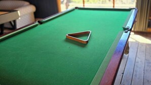 Ein Billardtisch mit einer dreieckigen weißen Kugel in der Mitte, bedeckt mit grünem Filz.