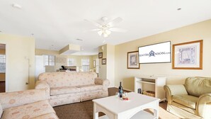 A spacious living room with a beige sofa, a white coffee table, and a ceiling fan.