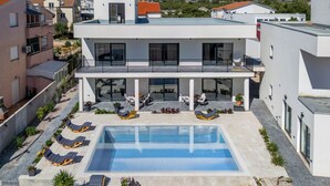 A modern building with a rooftop pool, lounge chairs, and potted plants. - Villa Claudio With Private Pool (Vodice)