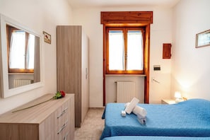 A bedroom with a bed, a dresser, a radiator, and a window.