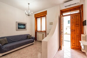 A living room with a sofa, a chandelier, a framed picture, a wooden door, and a radiator.