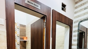 A bathroom with a wooden door labeled "WASH ROOM," a sink, and a mirror. - Deena Residency (Varanasi)
