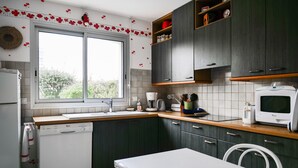 Eine Küche mit dunklen Schränken, einem weißen Geschirrspüler, einem Fenster und einer Mikrowelle.
