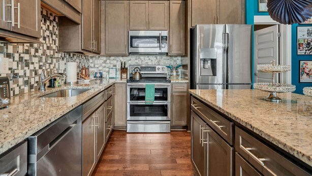 Une cuisine moderne avec des meubles en bois, des appareils électroménagers en acier inoxydable, un dosseret carrelé et un mur d’accent de couleur turquoise.