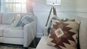 Ein Wohnzimmer mit einer Couch, einer Stehlampe und einem gemusterten Zierkissen.