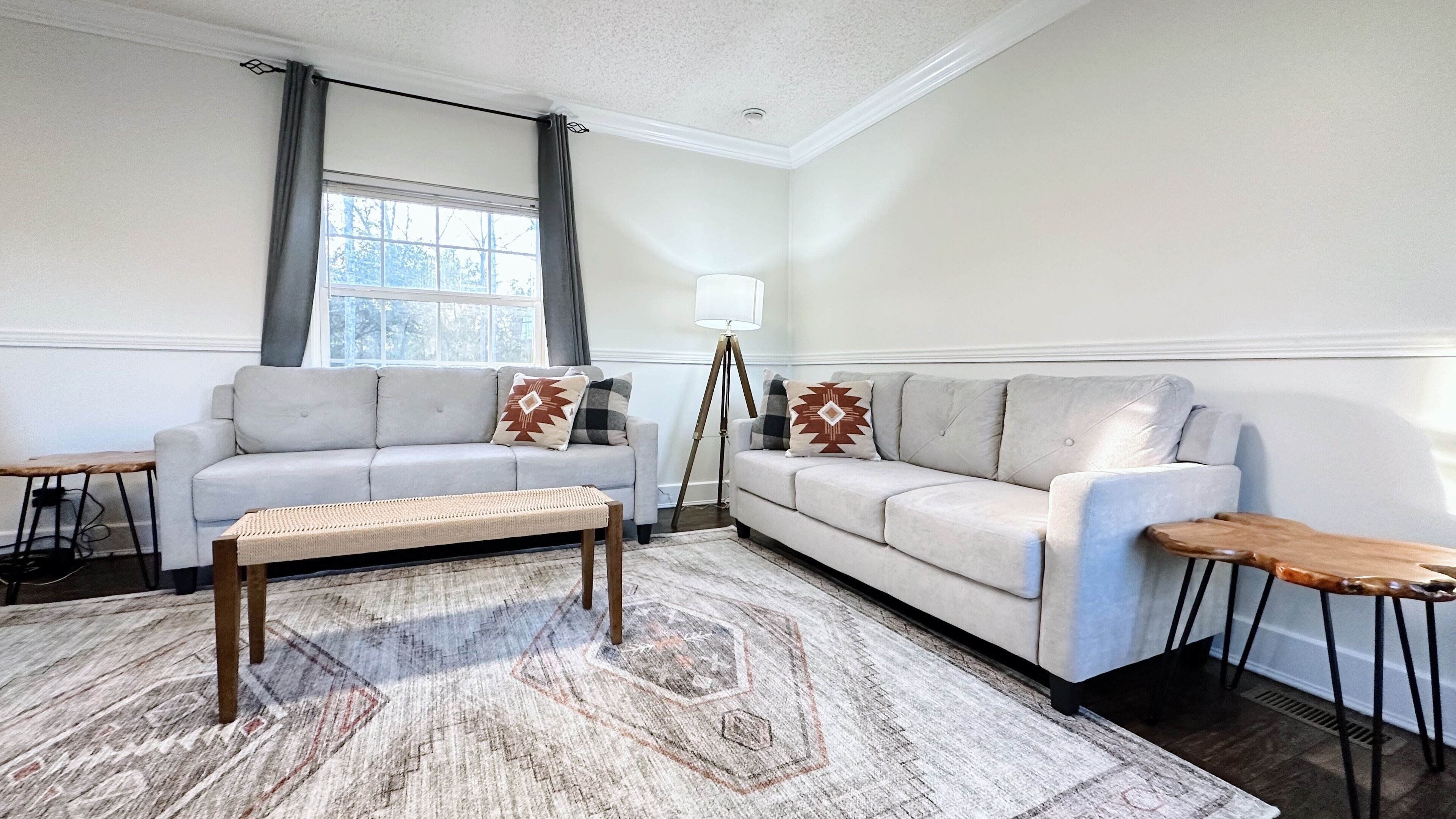 A living room with a light grey sofa, a wooden coffee table, and a patterned rug.