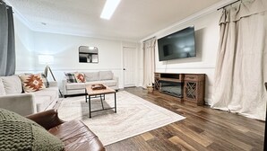 Ein modernes Wohnzimmer mit einer Couch, einem Couchtisch und einem an der Wand befestigten Flachbildfernseher.