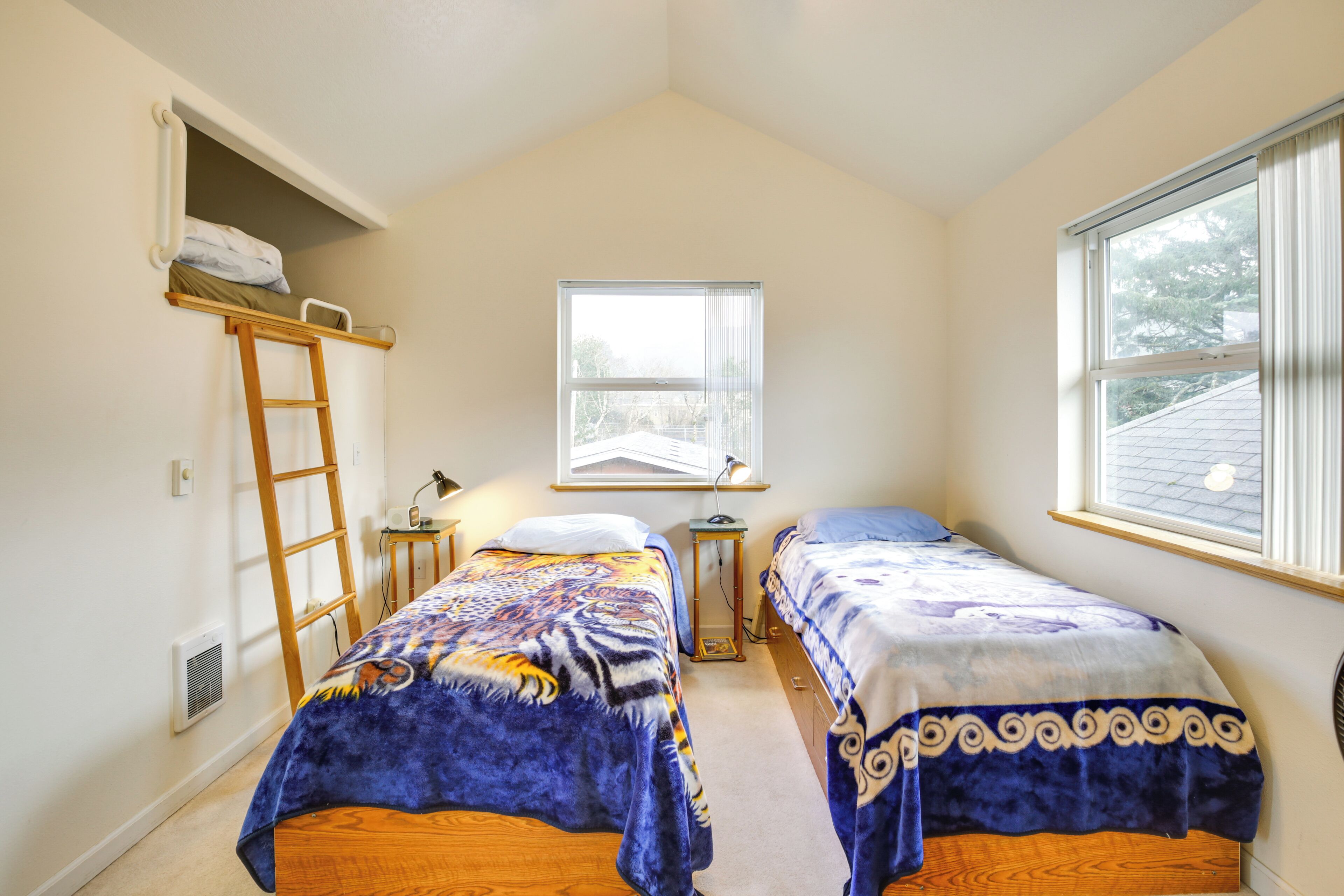 Une chambre avec deux lits, une échelle, une fenêtre et un bureau.