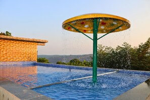 Une piscine agrémentée d’un élément décoratif aquatique et bordée de carreaux.