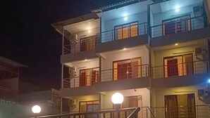 A multi-story building with balconies, a staircase, and a well-lit entrance. - Melody 24 East Resort (Mahabaleshwar)