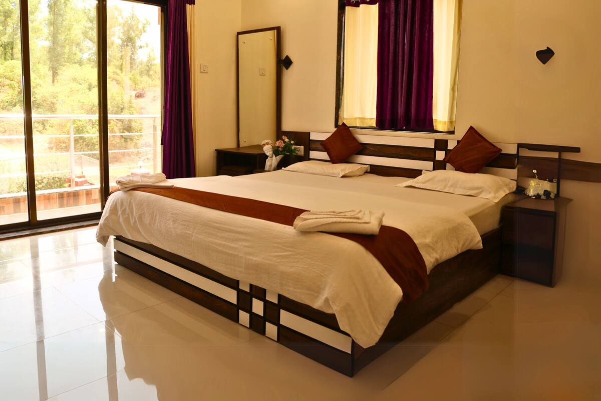 A large bed with a wooden frame, a nightstand, a mirror, and a window with curtains.