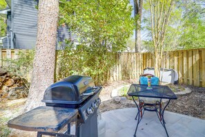 Een achtertuin met een barbecue, een tafel en een stoel.