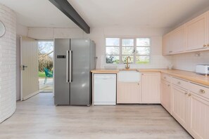 A modern kitchen with a stainless steel refrigerator, a dishwasher, and light-colored cabinets.
