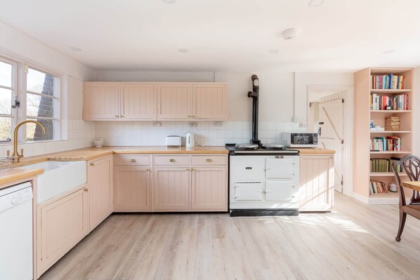 A modern kitchen with light wood cabinets, a built-in oven, and a microwave.