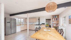 Una cocina moderna con una mesa de comedor de madera, electrodomésticos integrados y un ventanal grande.