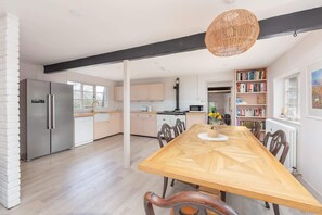 Une cuisine moderne avec une table à manger en bois, des appareils électroménagers intégrés et une grande fenêtre.