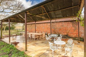 An outdoor patio with a covered seating area, a brick wall, and a garden.