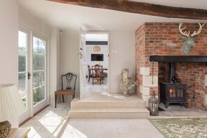 A spacious living area with a fireplace, a dining table with chairs, and a statue.