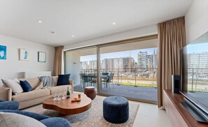 Relax in this stylish living room with a large flat-screen TV, comfortable sofa, and city views.