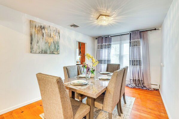 A dining area with a marble table, four upholstered chairs, a vase with flowers, and a painting on the wall. - Work, Explore & Relax: Centrally Located Union Gem (Union)
