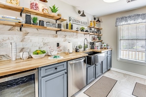 A modern kitchen with marble backsplash, wooden shelves, and a built-in dishwasher. - 4 Mi to Airport: Atlanta Home w/ Deck & Hot Tub (Atlanta)