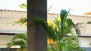 A modern outdoor seating area with a concrete table, a sofa, and a potted plant. - Bellevue Berawa Managed by CPM Bali (Canggu)
