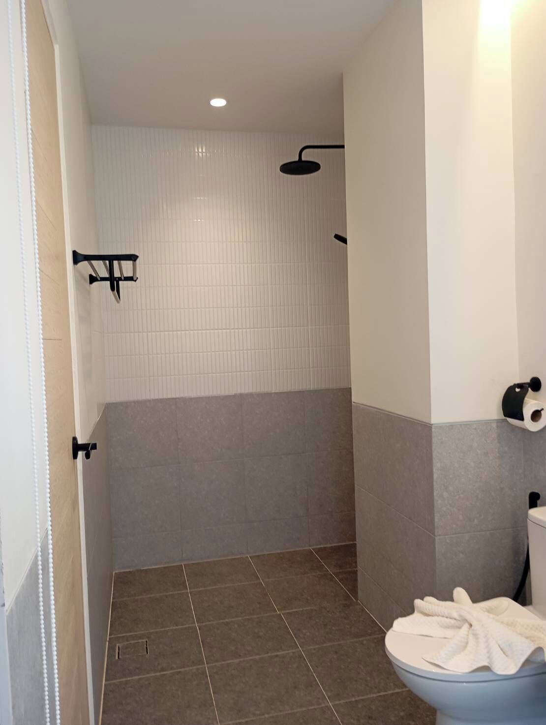 A bathroom with a shower, toilet, and towel rack.