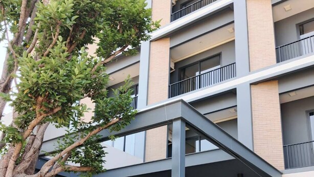 Un bâtiment moderne doté d’un porche, d’un arbre et d’une statue de chat décorative.