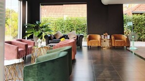 Un intérieur moderne avec un plafond sombre, un lustre et un espace salon comprenant des canapés et des fauteuils.