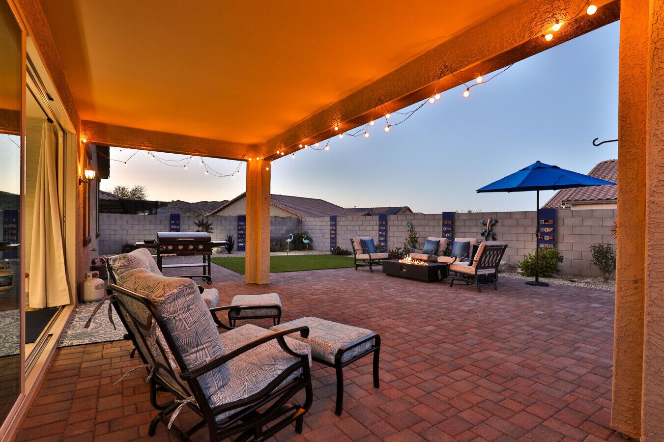 An outdoor patio with brick flooring, a barbecue grill, and outdoor furniture.