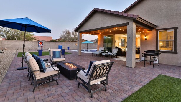 An outdoor patio with brick flooring, outdoor furniture, a fire pit, and string lights.