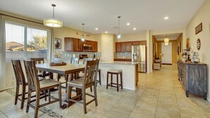 A spacious kitchen with a central island, wooden chairs, and a dining table.