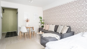 A modern bedroom with a grey sofa, a small round table, and a white bed. - Cozy 1BR Downtown Home next to all Restaurants (Tampere)