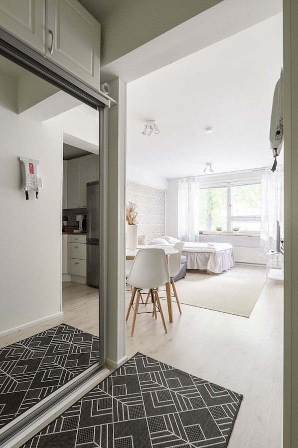 Una habitación moderna y luminosa con cama, mesita de noche y ventana con cortinas.