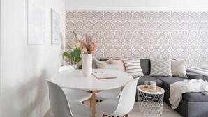 A modern living room with a round dining table, white chairs, a grey sofa, and patterned wallpaper. - Cozy 1BR Downtown Home next to all Restaurants (Tampere)