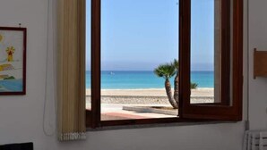 A room with a large window offering a view of a beach and the sea. - ON THE WATERFRONT UNIQUE LOCATION!!!! (San Vito Lo Capo)