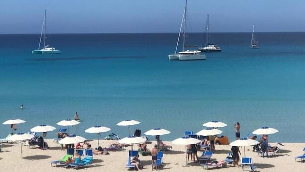 A beach with several sailboats in the water and multiple beach umbrellas providing shade. - ON THE WATERFRONT UNIQUE LOCATION!!!! (San Vito Lo Capo)