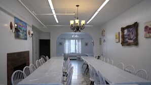 A conference room with a long table, white chairs, a chandelier, and artwork on the walls.