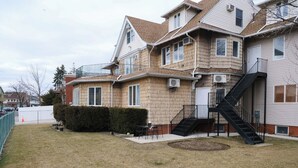 A two-story house with a front yard, a staircase, and a fenced area.